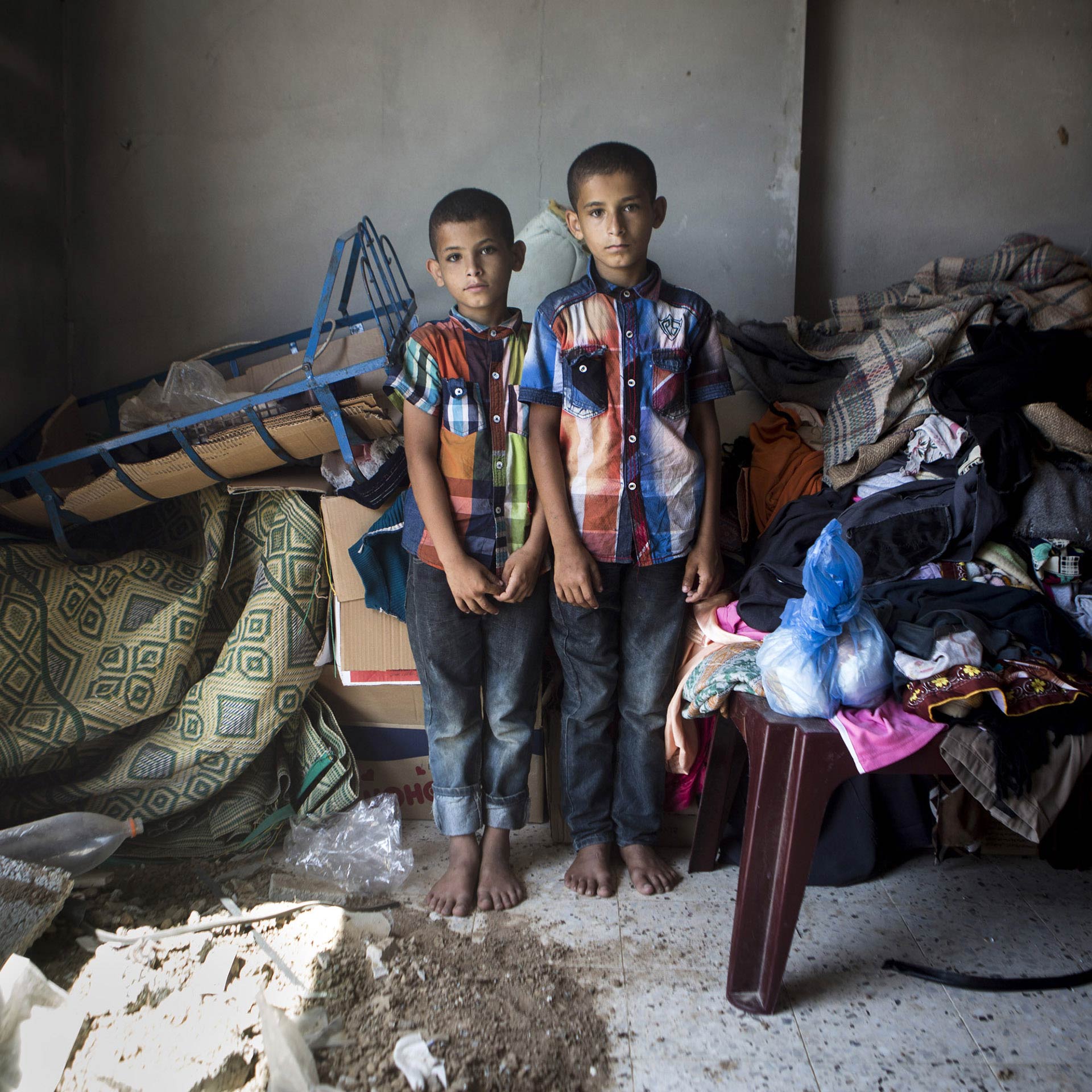 Ibrahim, le plus jeune des frères jumeaux sur la photo, dit son meilleur ami, Maysara Al-Louh, sept ans, lui manque. Les deux garçons, Ibrahim et son frère Abdalallah, se tiennent au milieu de leur chambre détruite. Leur maison, située juste en face de la maison des al-Louh, fut endommagée dans les bombardements qui tuèrent Maysara et sept autres membres de la famille Al-Louh.
